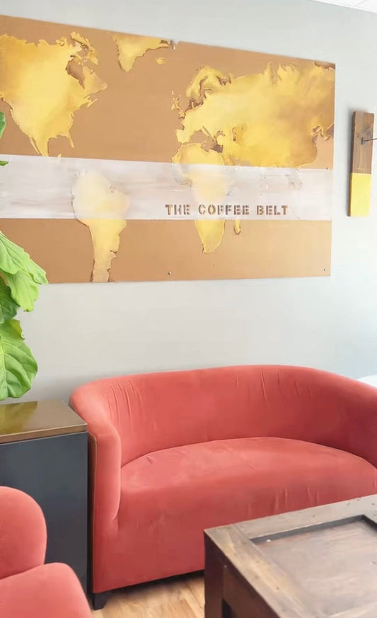 A corner of a cafe with a red couch and a wall hanging showing a world