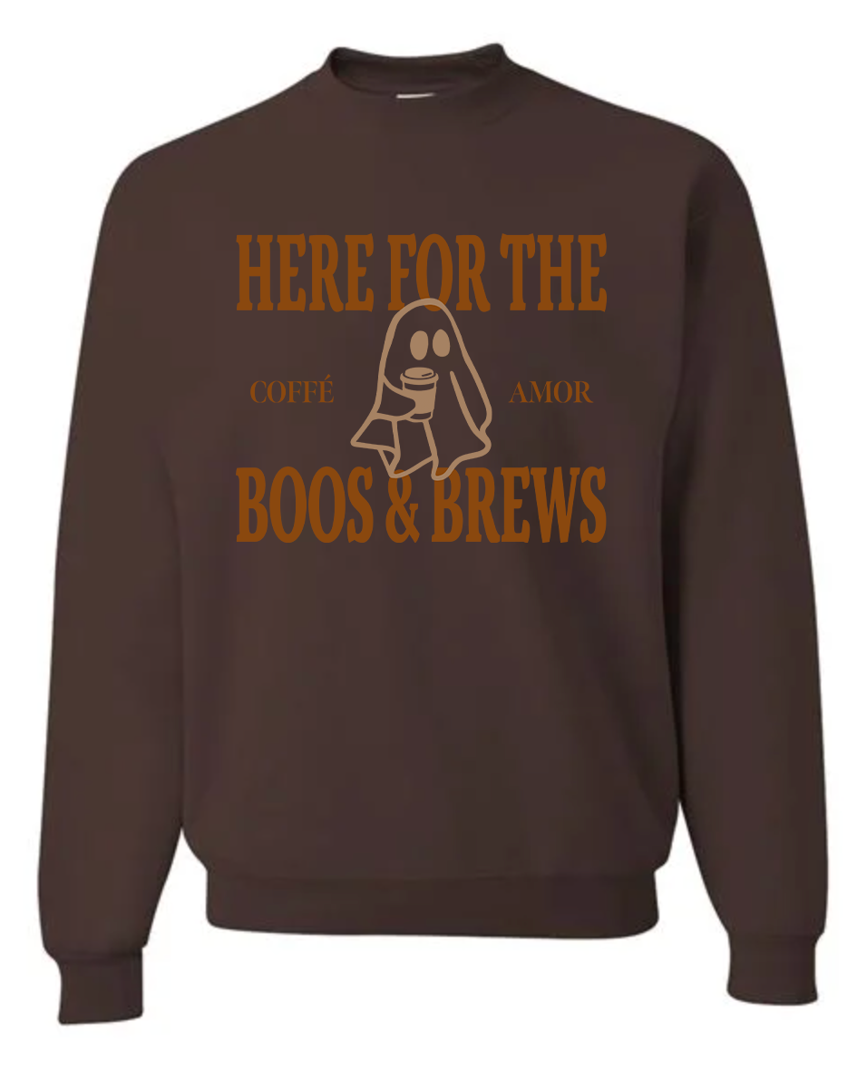 A dark brown crewneck sweatshirt featuring a graphic print with the text 'HERE FOR THE COFFEE AMOR BOOS & BREWS' and a ghost illustration in a tan color, displayed on a solid white background.